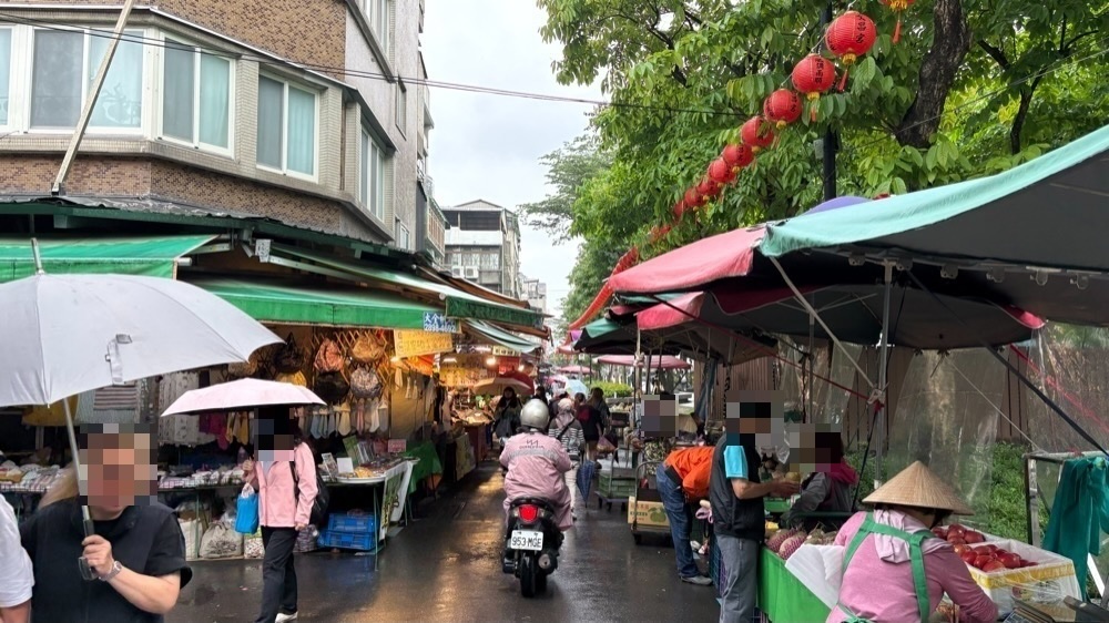 雨の雙連朝市。傘をさした買い物客と、果物や乾物を売る屋台が並ぶ通り