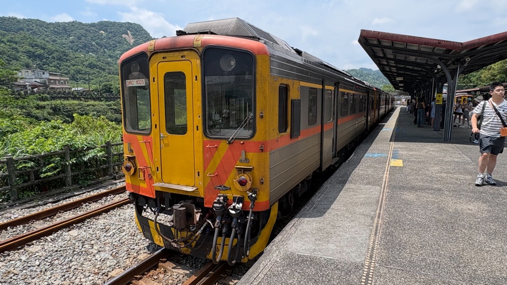 十分駅に停車する黄色とオレンジの平渓線の電車