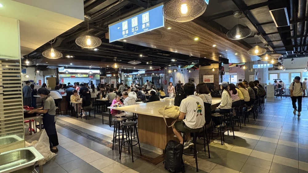 華山市場2階のフードコート。カウンター席とテーブル席が並び、多くの人が食事をしている