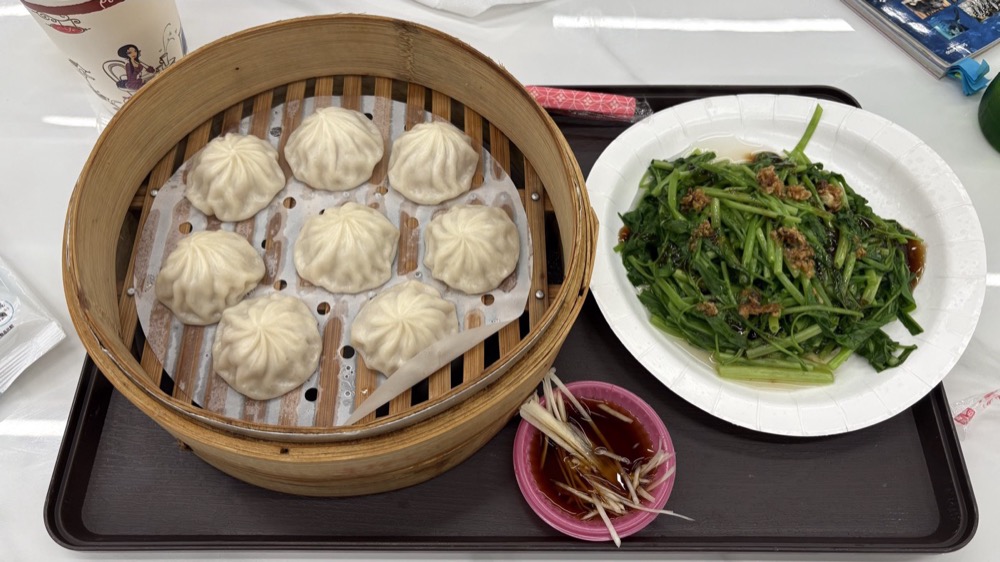 せいろに入った小籠包と、紙皿に盛られた青菜炒め