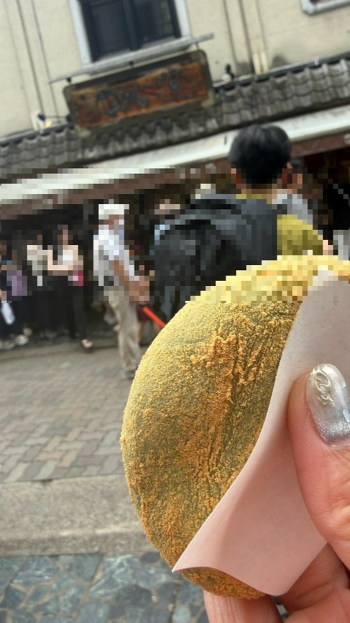 中谷堂のよもぎ餅。きな粉がまぶしてあり、紙に包んで手に持っている