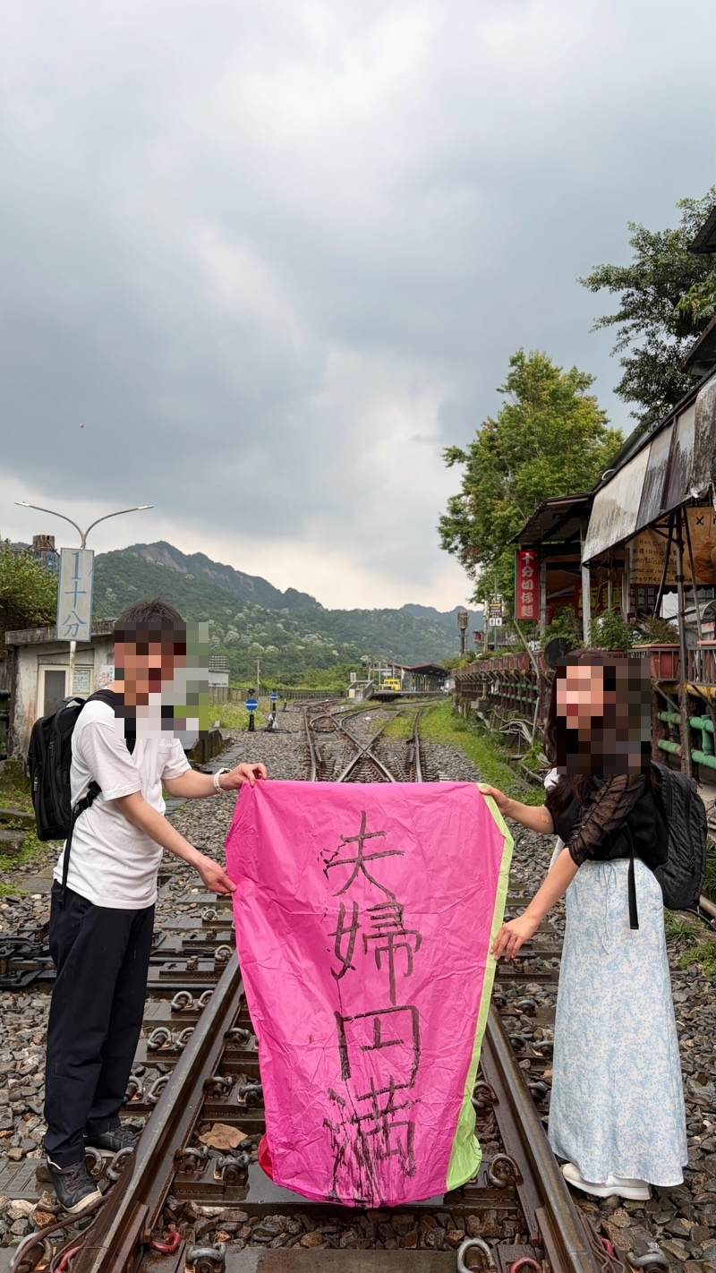 十分の線路の上で、願いごとを書いたランタンを持つ夫婦
